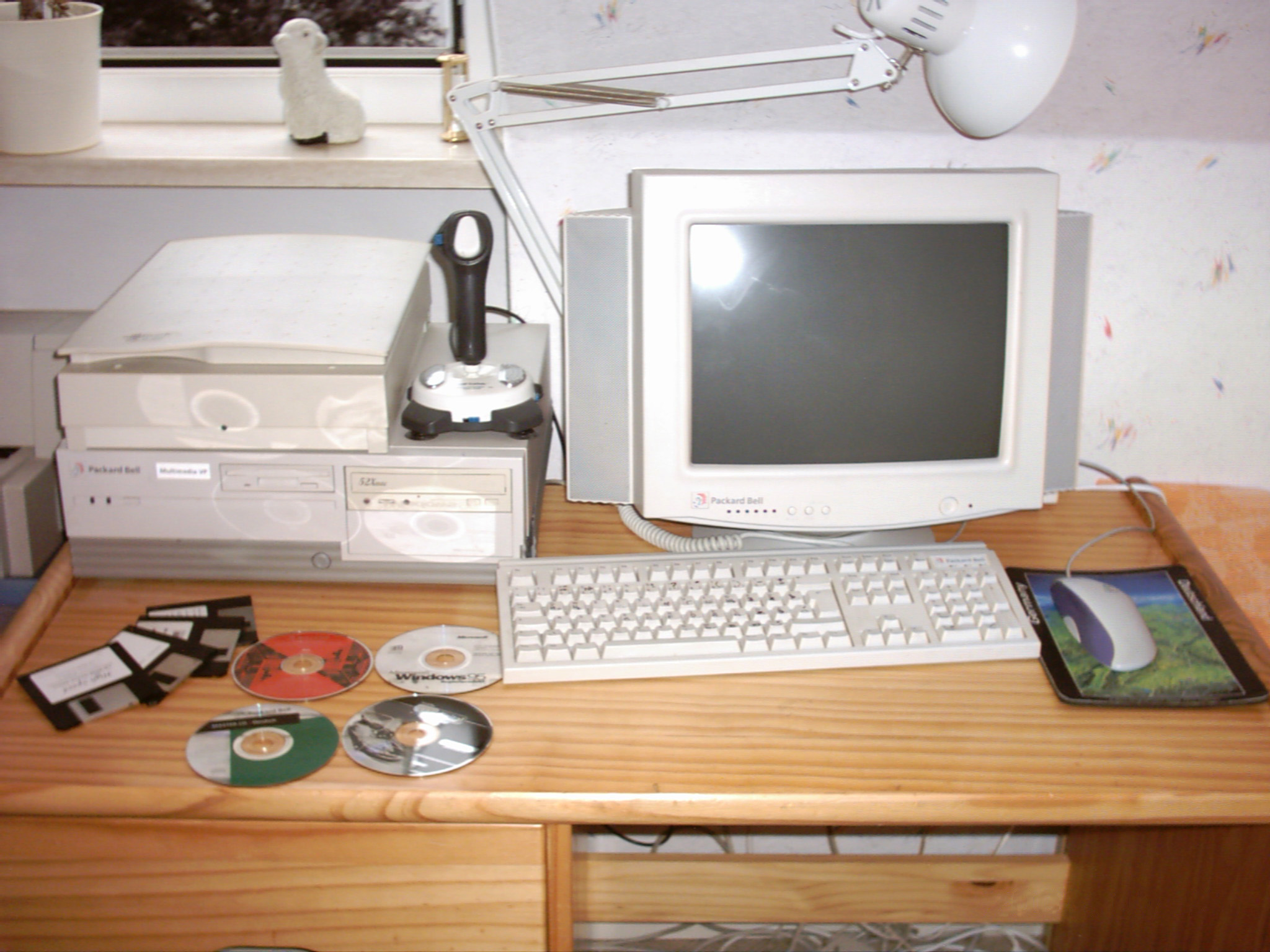 Vintage Packard Bell desktop computer with CRT monitor, keyboard, floppy disks, and CDs